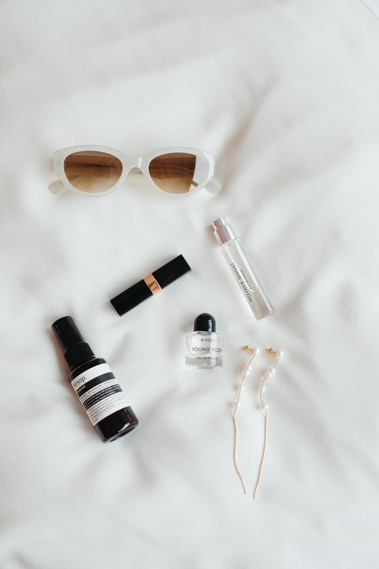 Accessoires für die Hochzeit: Sonnenbrille, Parfum, Deodorant, Lippenstift und Ohrringe. Fotografiert von Laura-Sophie Jung, Hochzeitsfotografin Berlin und deutschlandweit.
