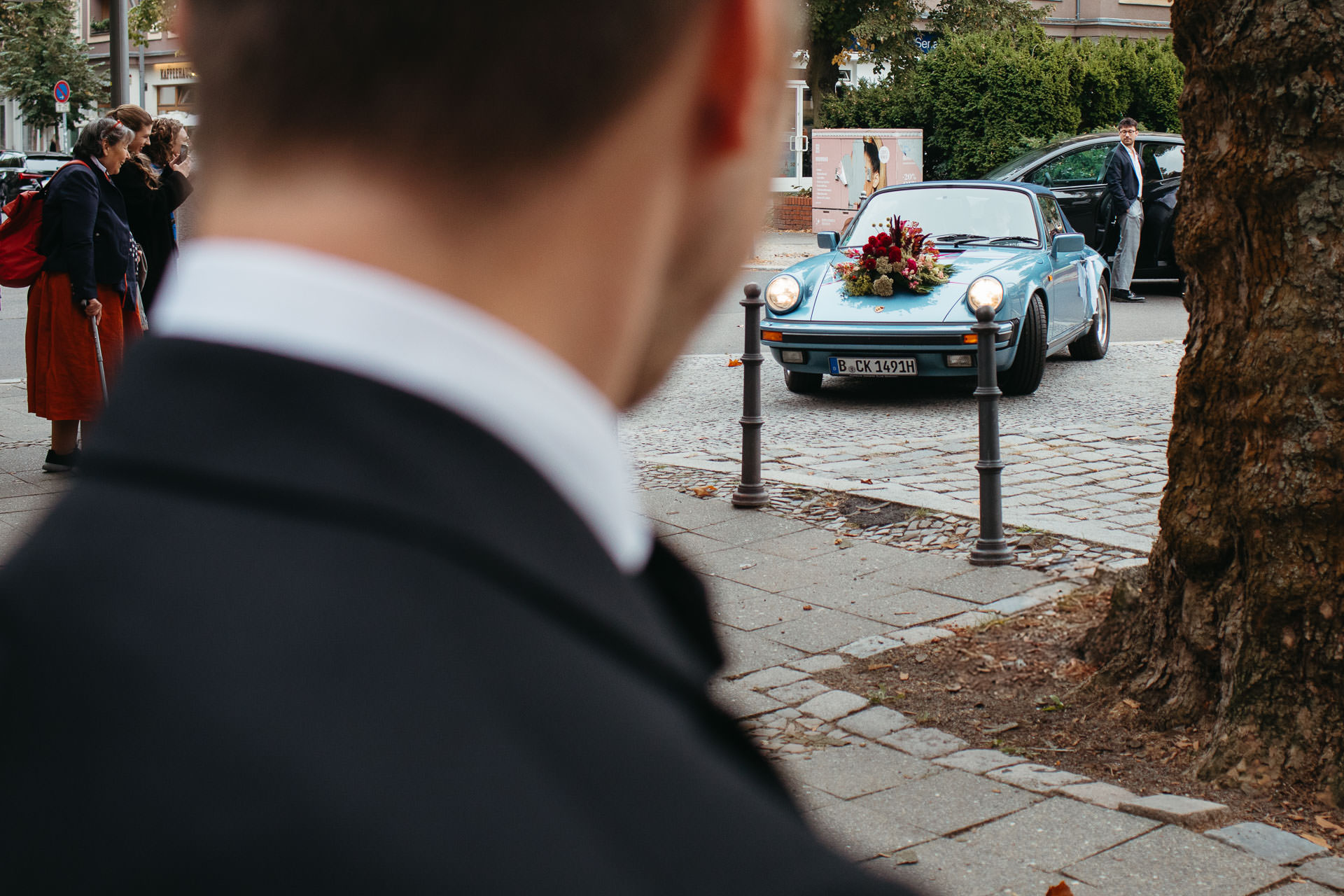 Ankunft beim Standesamt im Hochzeitsauto, einem Porsche Oldtimer geschmückt mit Blumenbouquet. Foto von Laura-Sophie Jung.