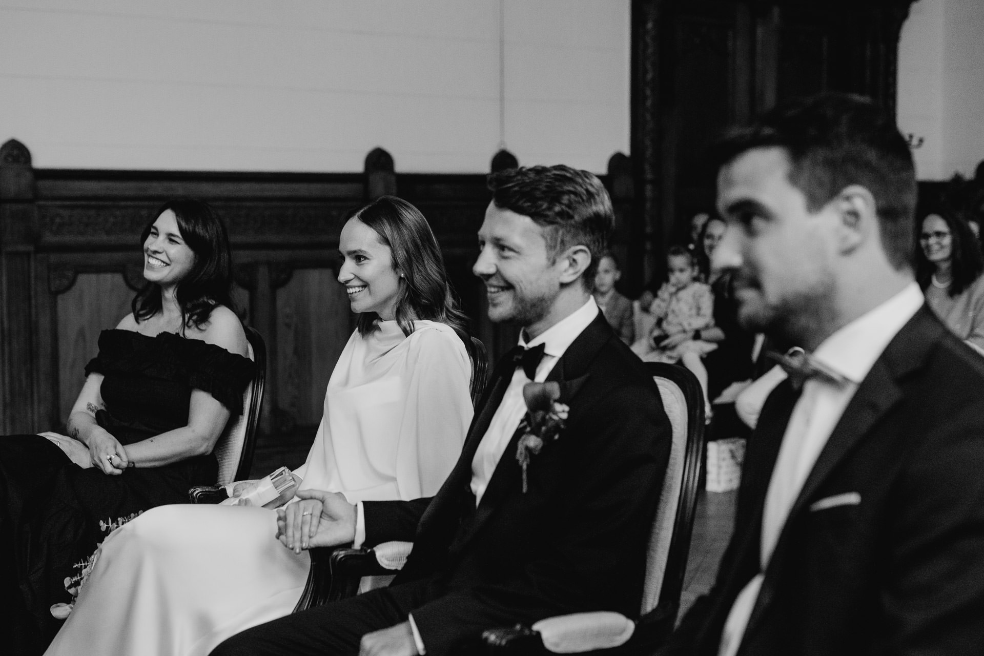 Standesamtliche Trauung im Rathaus Schmargendorf, Berlin: Braut und Bräutigam, neben ihnen Trauzeuge und Trauzeugin während der Zeremonie. Foto in schwarz-weiß von Laura-Sophie Jung.