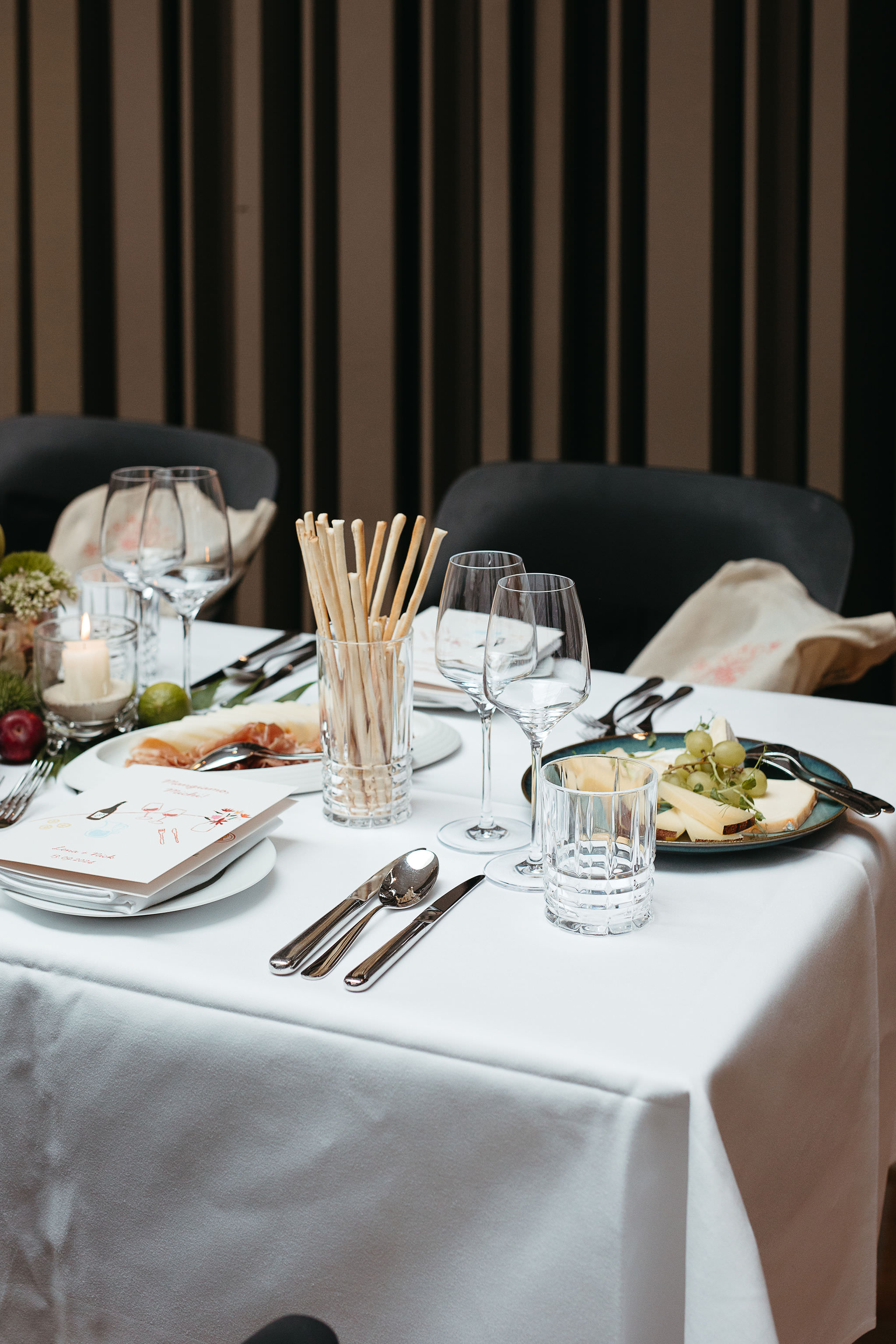 Gedeckter Tisch für das Hochzeitsessen mit Kerze, Blumendeko, Menükarte und Appetizern. Foto von Hochzeitsfotografin Berlin, Laura-Sophie Jung.