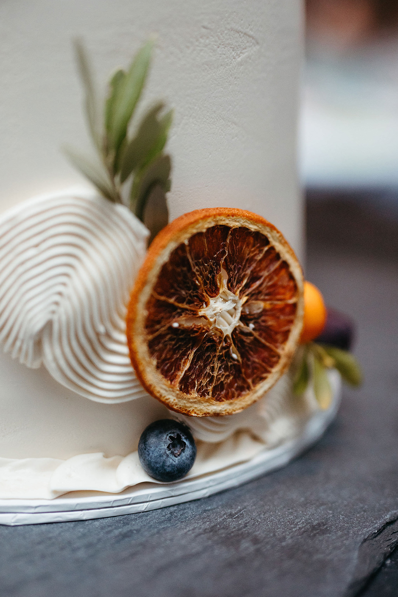 Hochzeitstorte - Detailaufnahme der Dekoration mit Beeren und Orangenscheibe. Bild von Hochzeitsfotografin Berlin, Laura-Sophie Jung.