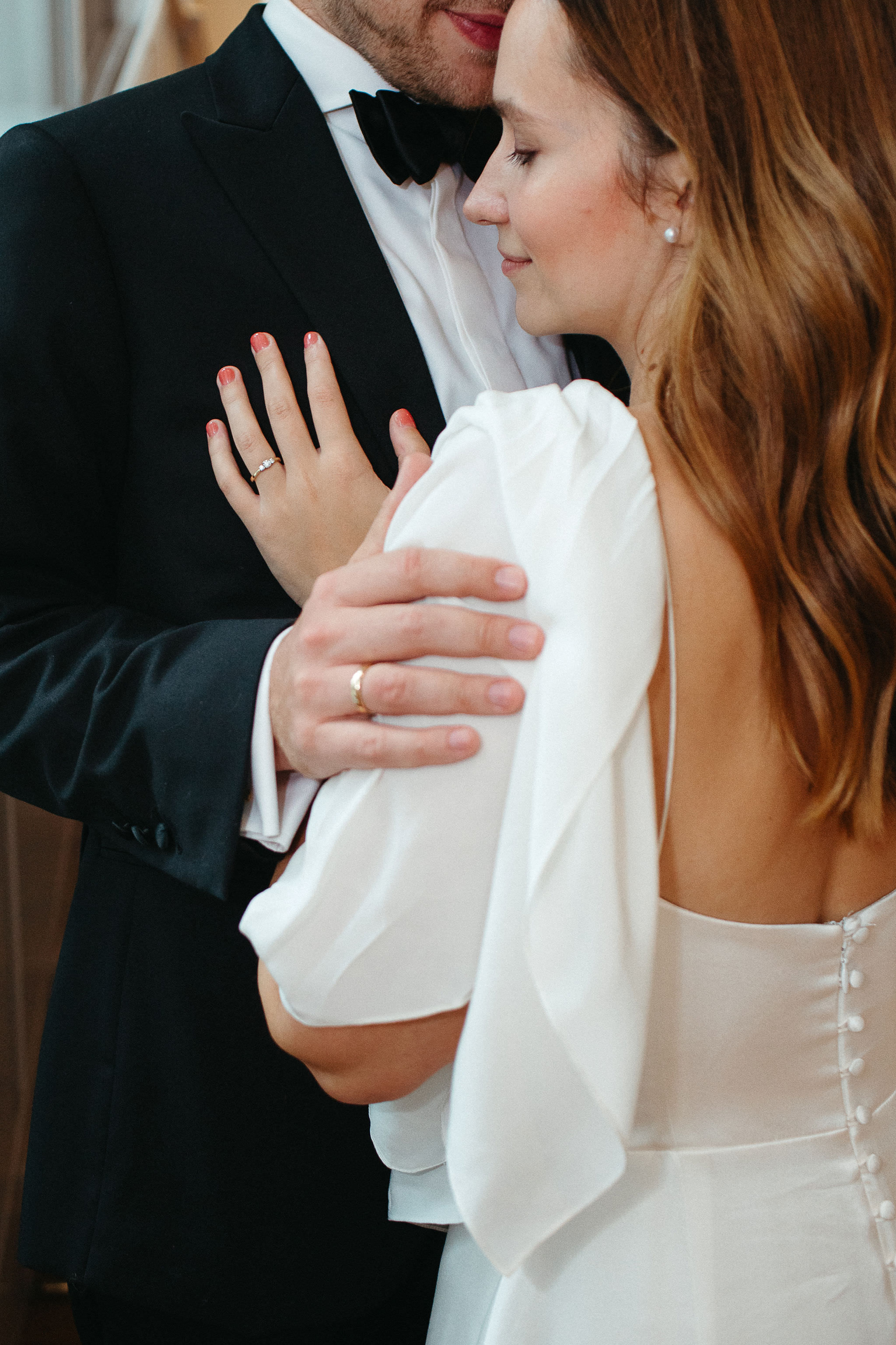 Emotionales Hochzeitsfotot: Braut und Bräutigam stehen eng beieinander, der Bräutigam neigt sich zärtlich zur Stirn der Braut, während beide sich innig festhalten. Fotografiert von Laura-Sophie Jung, Berlin.