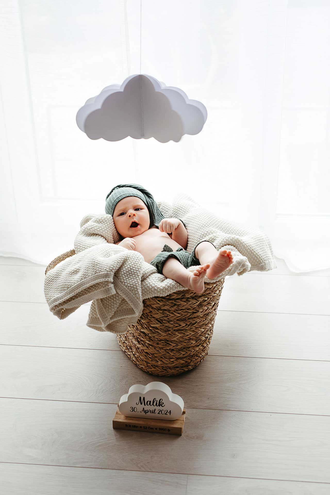 Niedliches Babyfoto: Müdes Baby liegt gähnend auf einer Decke in einem Korb. Fotografin: Laura-Sophie Jung.