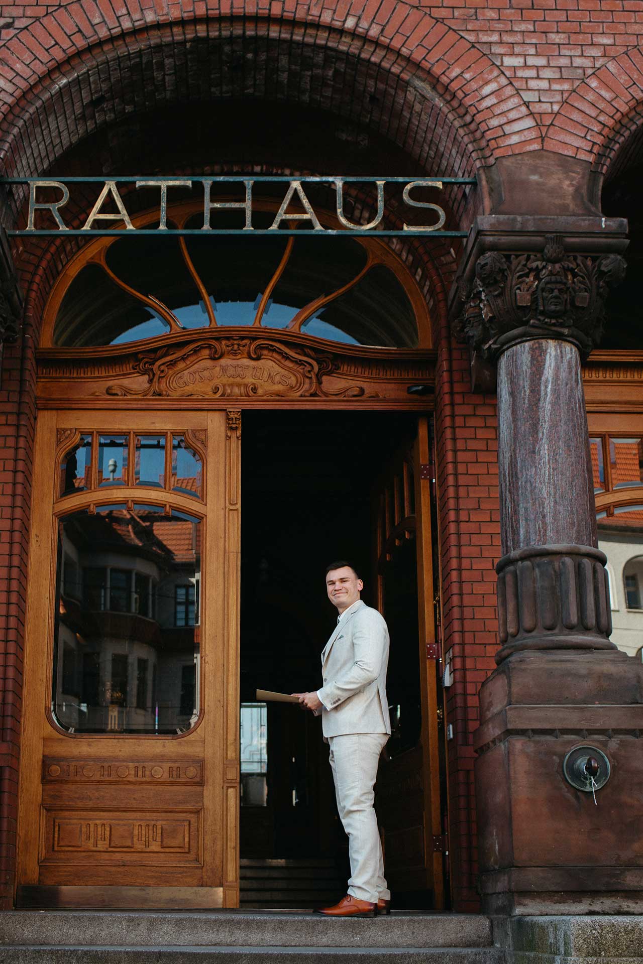 Hochzeitsfotos Standesamt: Bräutigam steht im Eingang des Rathaus Pankow. Fotografiert von Laura-Sophie Jung