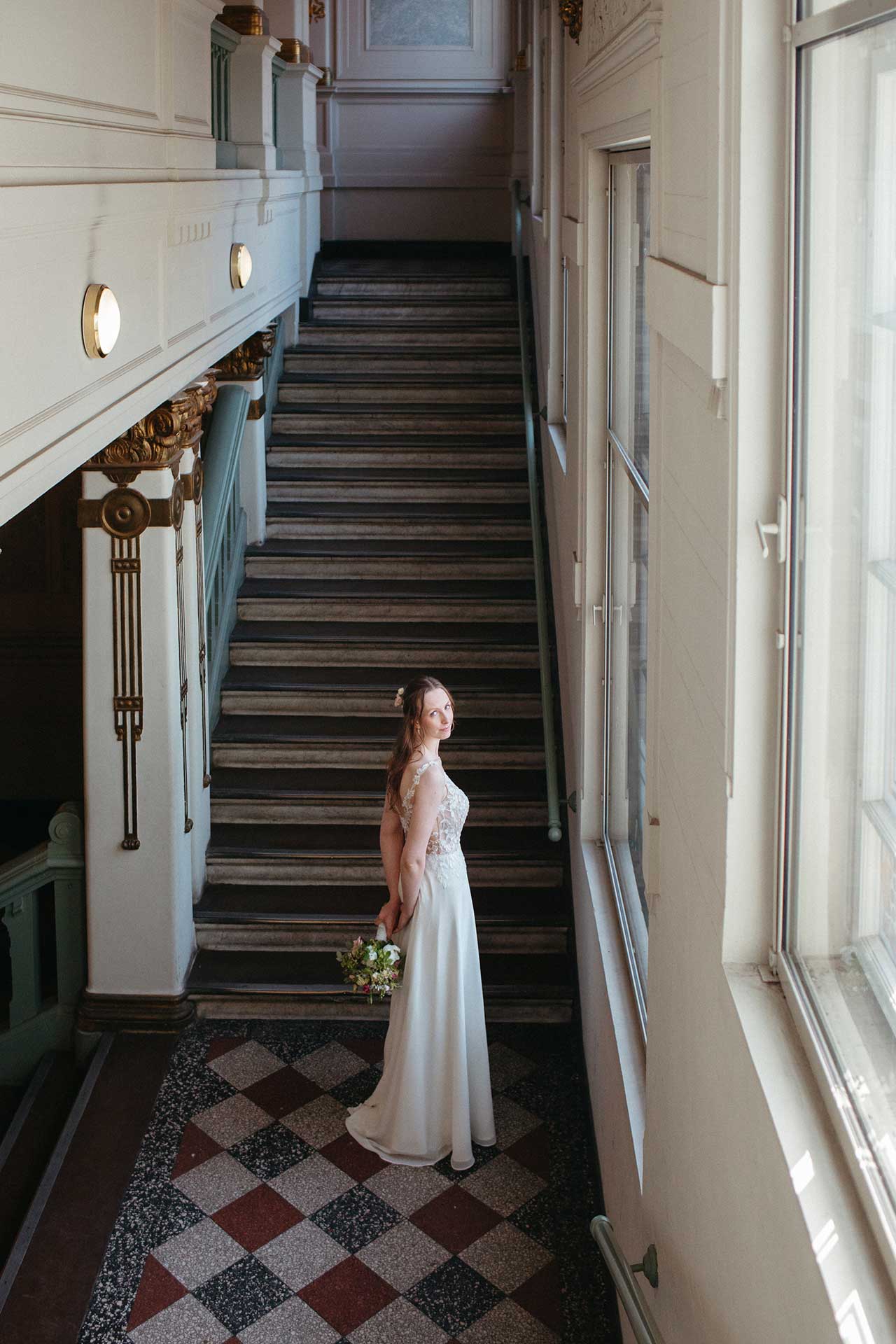 Hochzeitsfotos Standesamt: Braut steht im Treppenhaus vom Standesamt Pankow. Foto: Laura-Sophie Jung