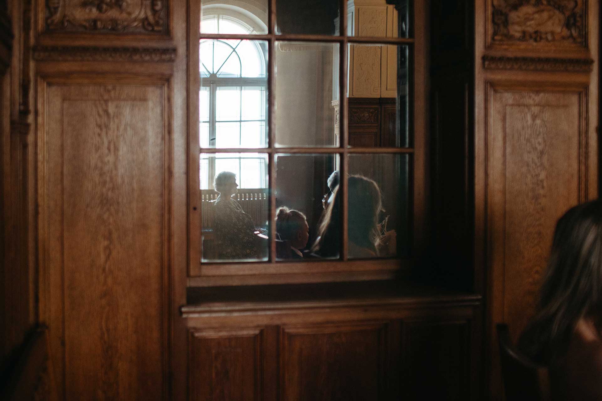 Hochzeitsfotos Standesamt: Spiegelung von Personen im Fenster. Fotografiert von Laura-Sophie Jung