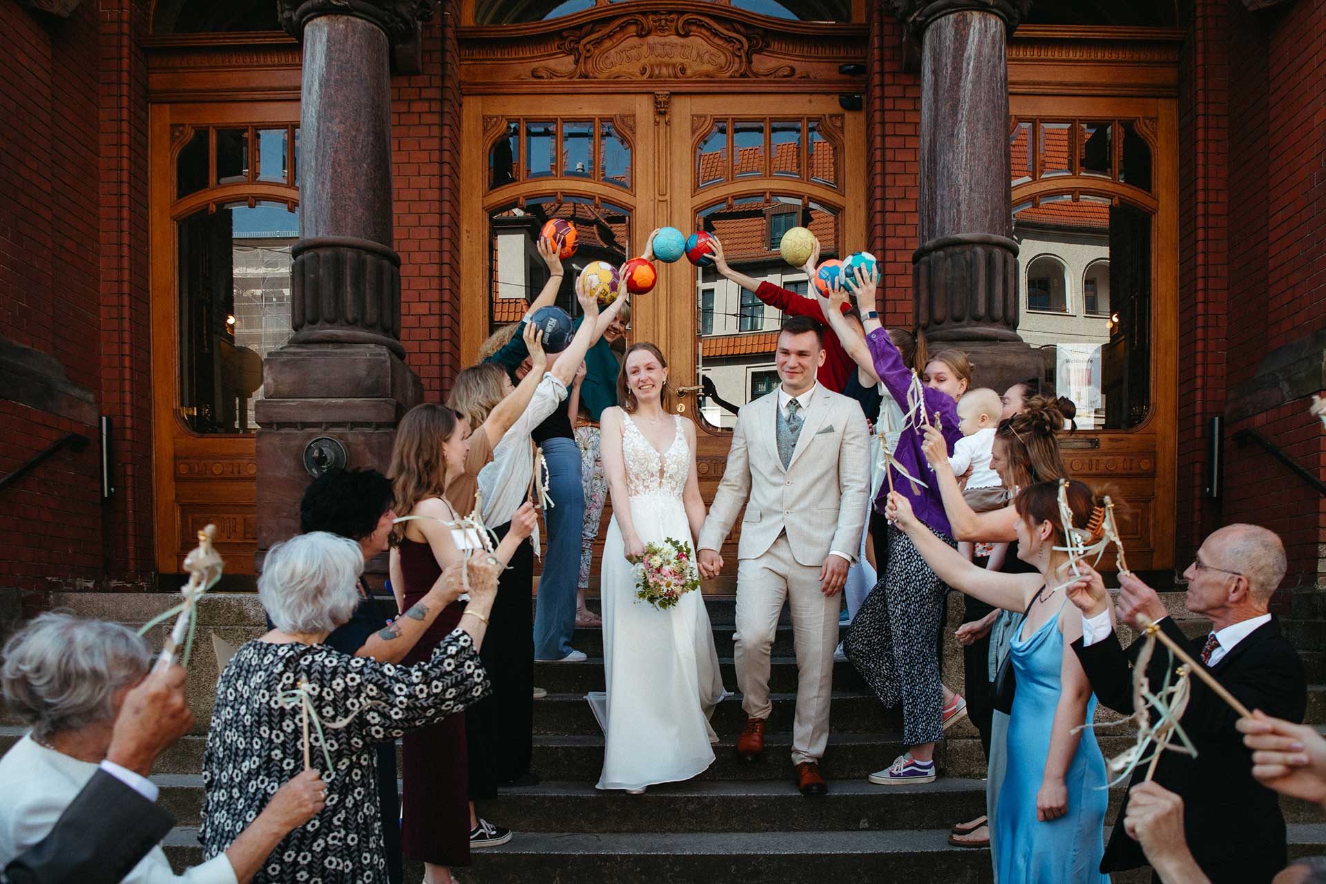 Hochzeitsfotos Standesamt: Paar läuft durch eine Menge Menschen mit Handbällen. Fotografiert von Laura-Sophie Jung