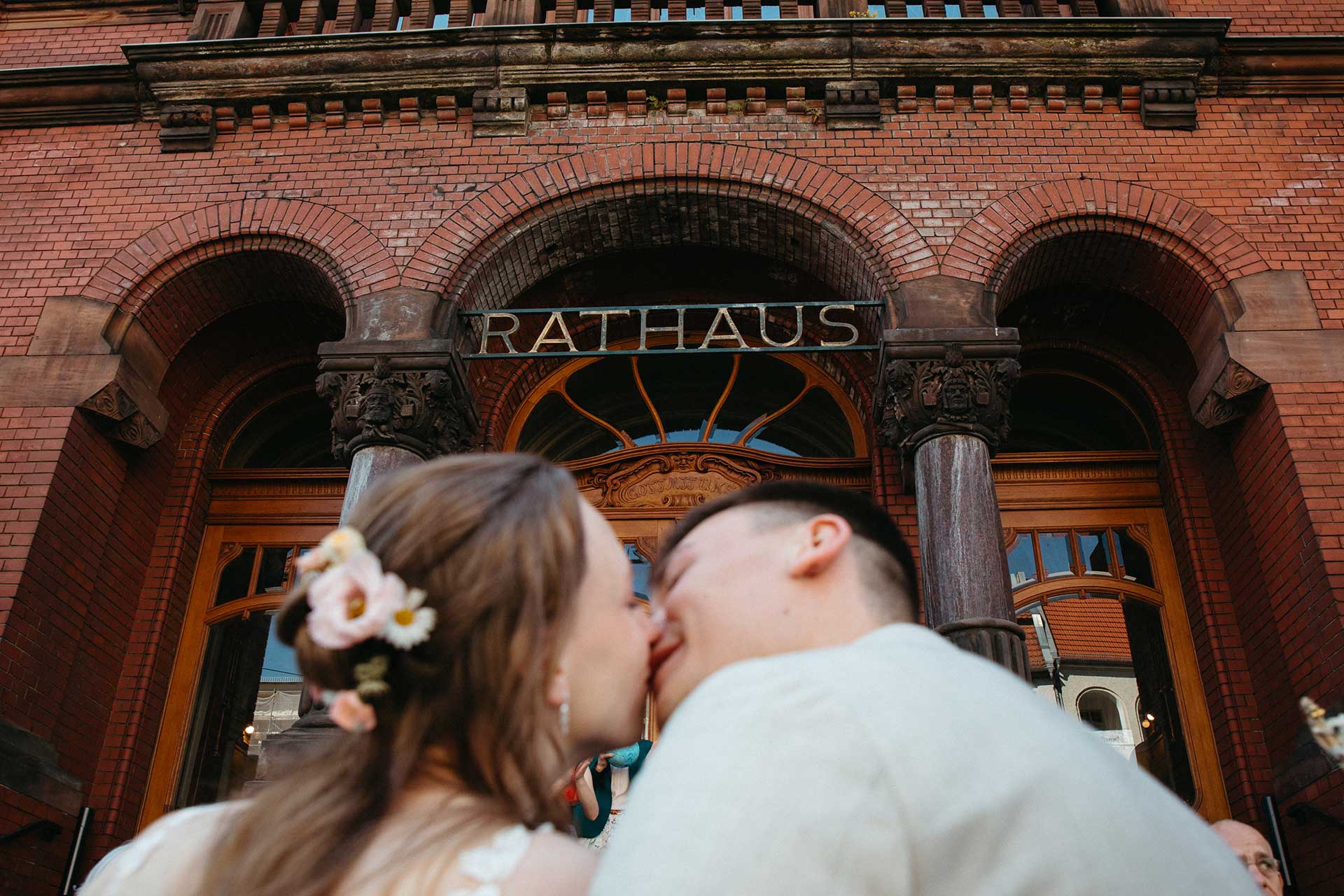 Hochzeitsfotos Standesamt: Paar küsst sich vor dem Rathausgebäude. Foto: Laura-Sophie Jung