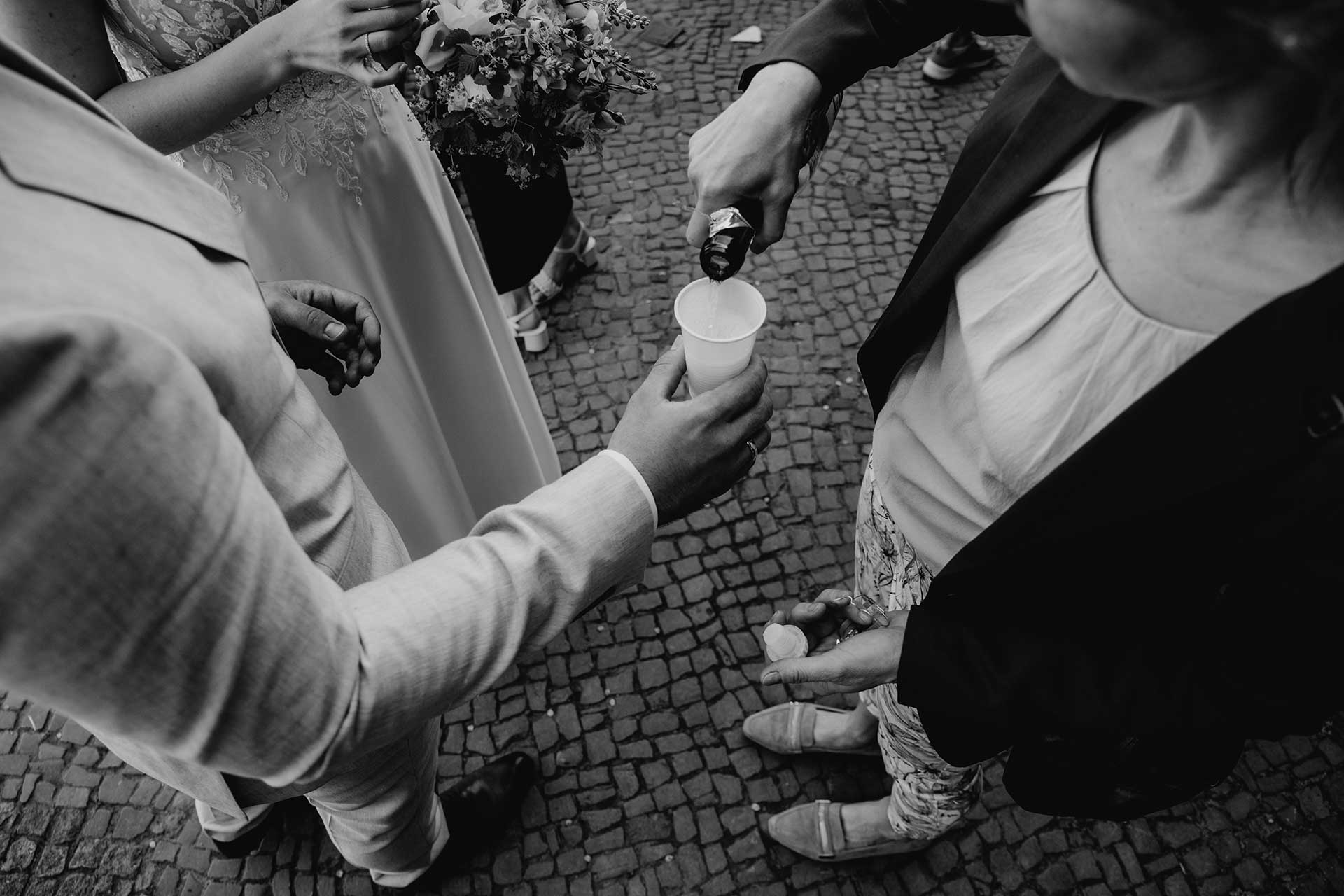 Hochzeitsfotos Standesamt: Sekt wird in Becher gefüllt. Fotografiert von Laura-Sophie Jung