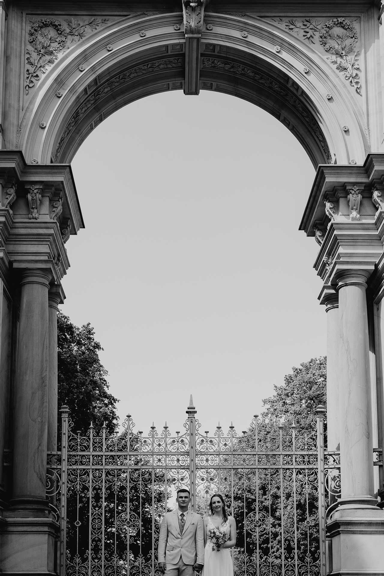 Hochzeitsfotos Standesamt: Paar steht nenebeinander unter Torbogen. Foto: Laura-Sophie Jung