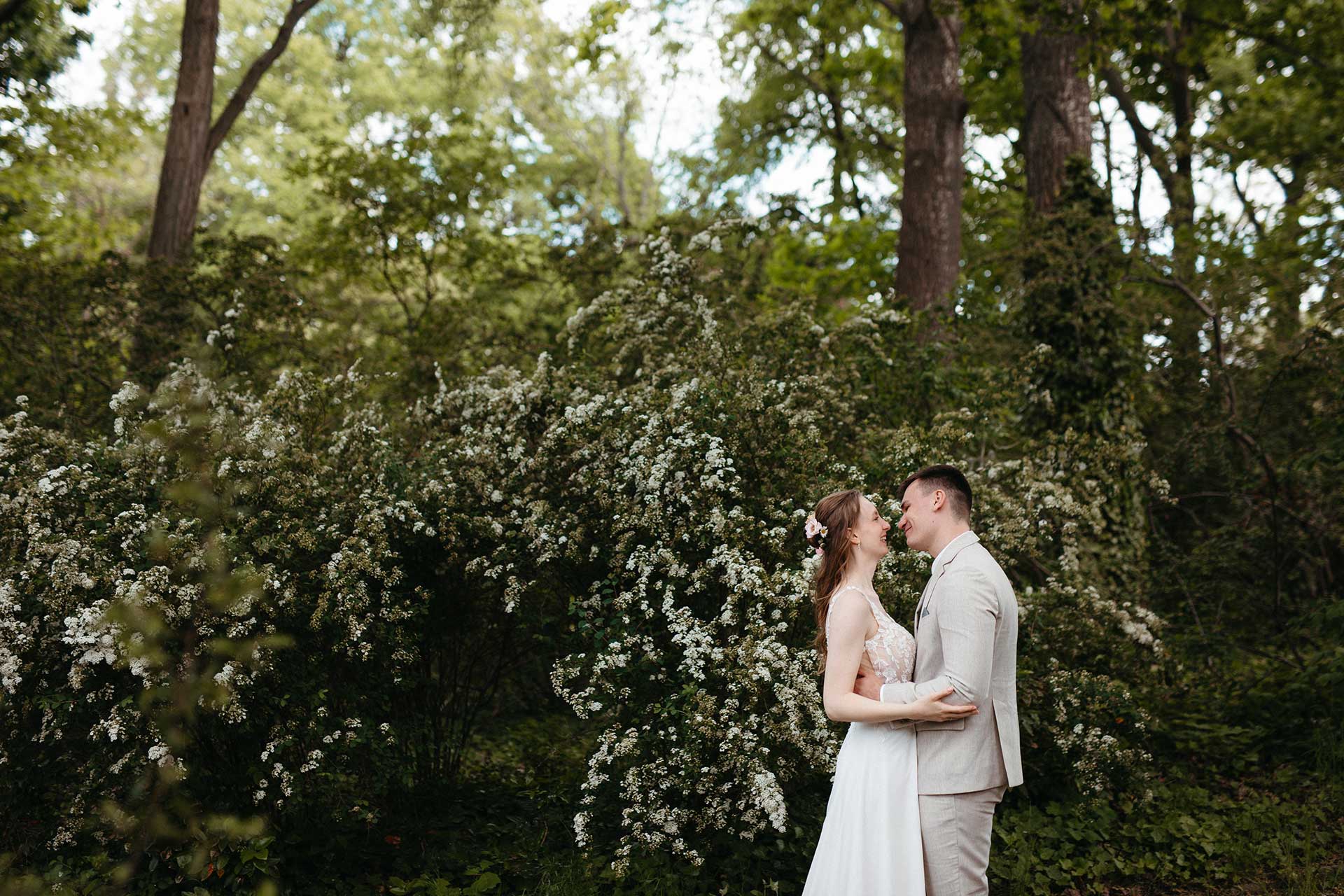 Hochzeitsfotos Standesamt: Paar steht vor blühendem Busch. Fotografiert von Laura-Sophie Jung