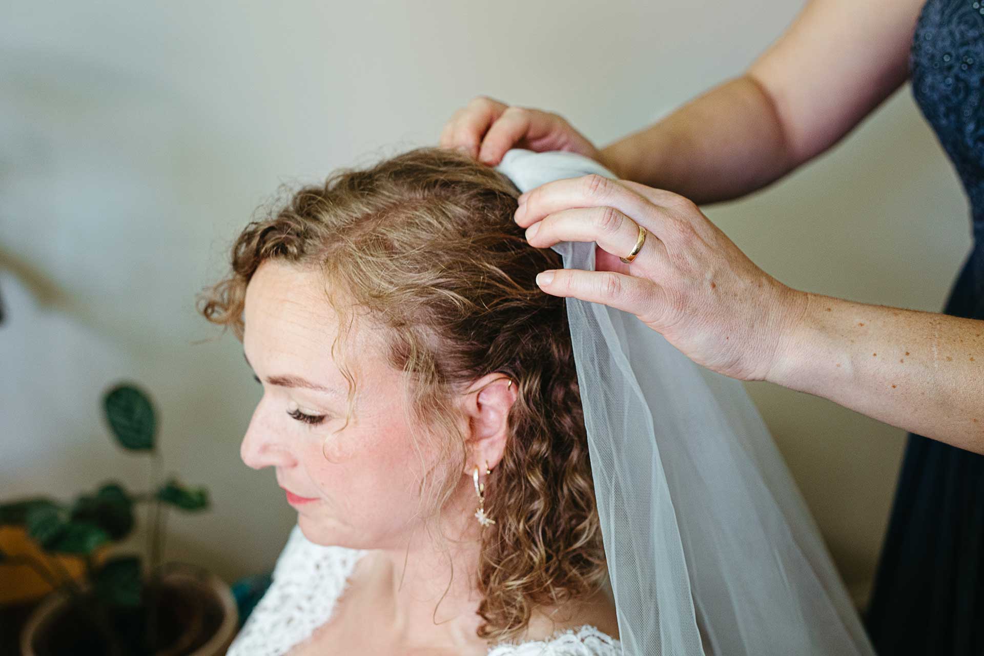 Vor der Hochzeit: Eine Helferin befestigt vorsichtig den Schleier an den Haaren der Braut. Bild von Laura-Sophie Jung.