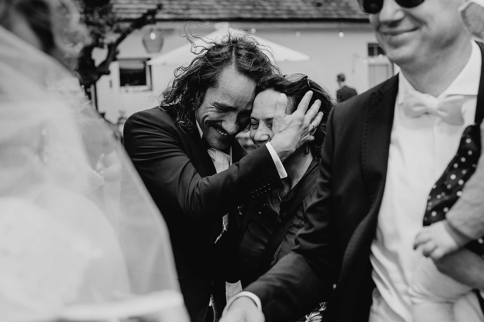 Hochzeitsfoto natürlich und ungestellt: Glücklicher Bräutigam mit einer Gratulantin. Bild in schwarz-weiß, fotografiert von Laura-Sophie Jung.