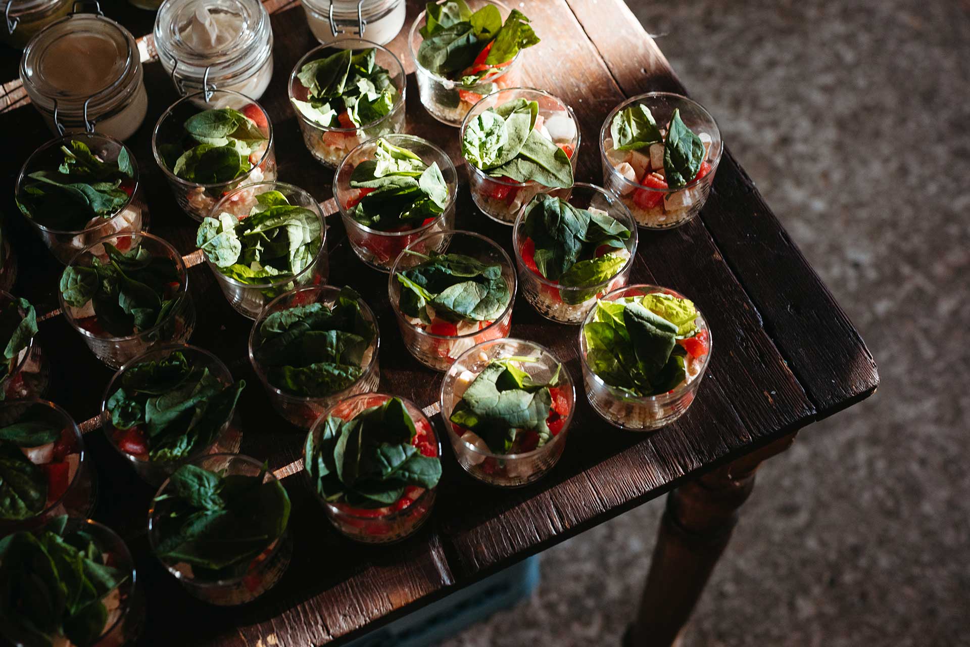 Essen bei der Hochzeitsfeier: Vorspeise in kleinen Gläsern mit Gemüse und frischem Spinat auf einem Holztisch. Fotografiert von Laura-Sophie Jung.