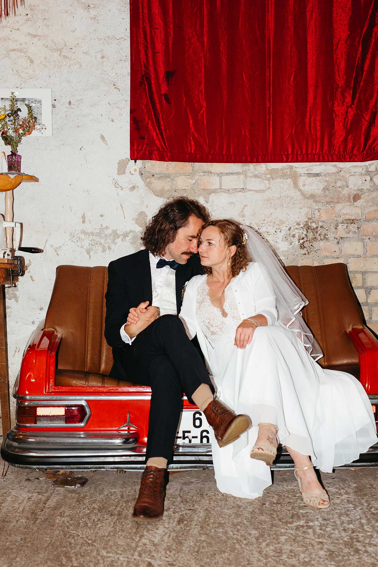 Am Ende des Hochzeitstages: Braut und Bräutigam sitzen müde auf einem Sofa im "Steinreich Leben". Foto von Laura-Sophie Jung, Hochzeitsfotografin Berlin, Brandenburg und deutschlandweit.