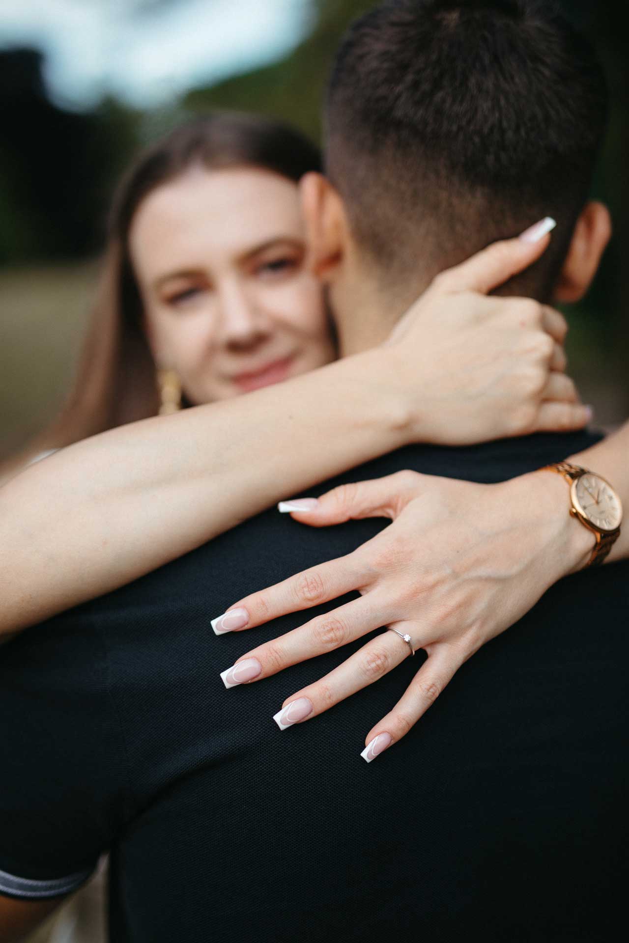 Verlobungsshooting outdoor: Paar umarmt sich. Im Fokus: Die Hand der Frau mit Verlobungsring. Fotografiert von Laura-Sophie Jung, Berlin.