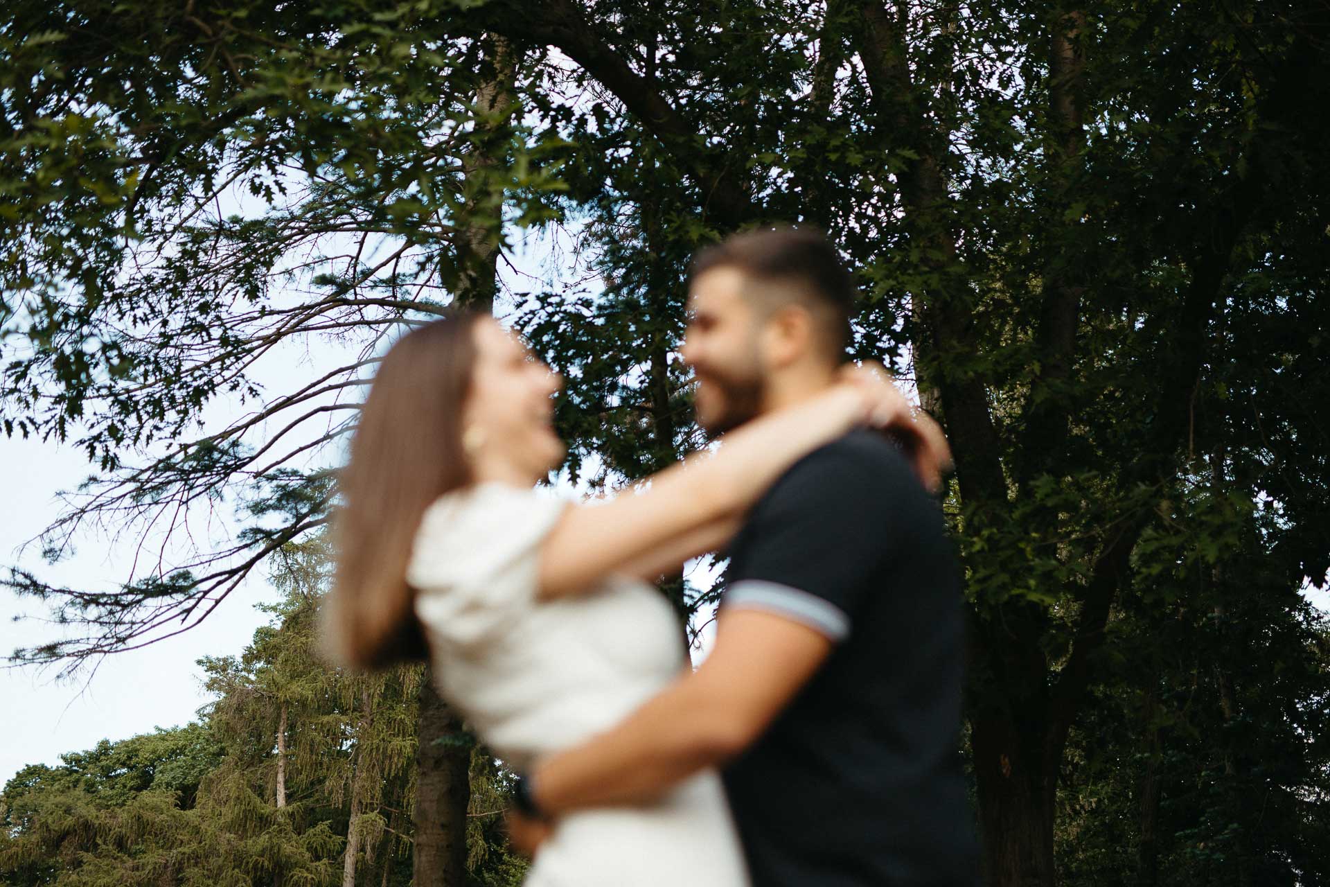 Paar beim Verlobungsshooting outdoor: Mann und Frau umarmen sich und lächeln sich an. Fotografiert von Laura-Sophie Jung, Berlin.