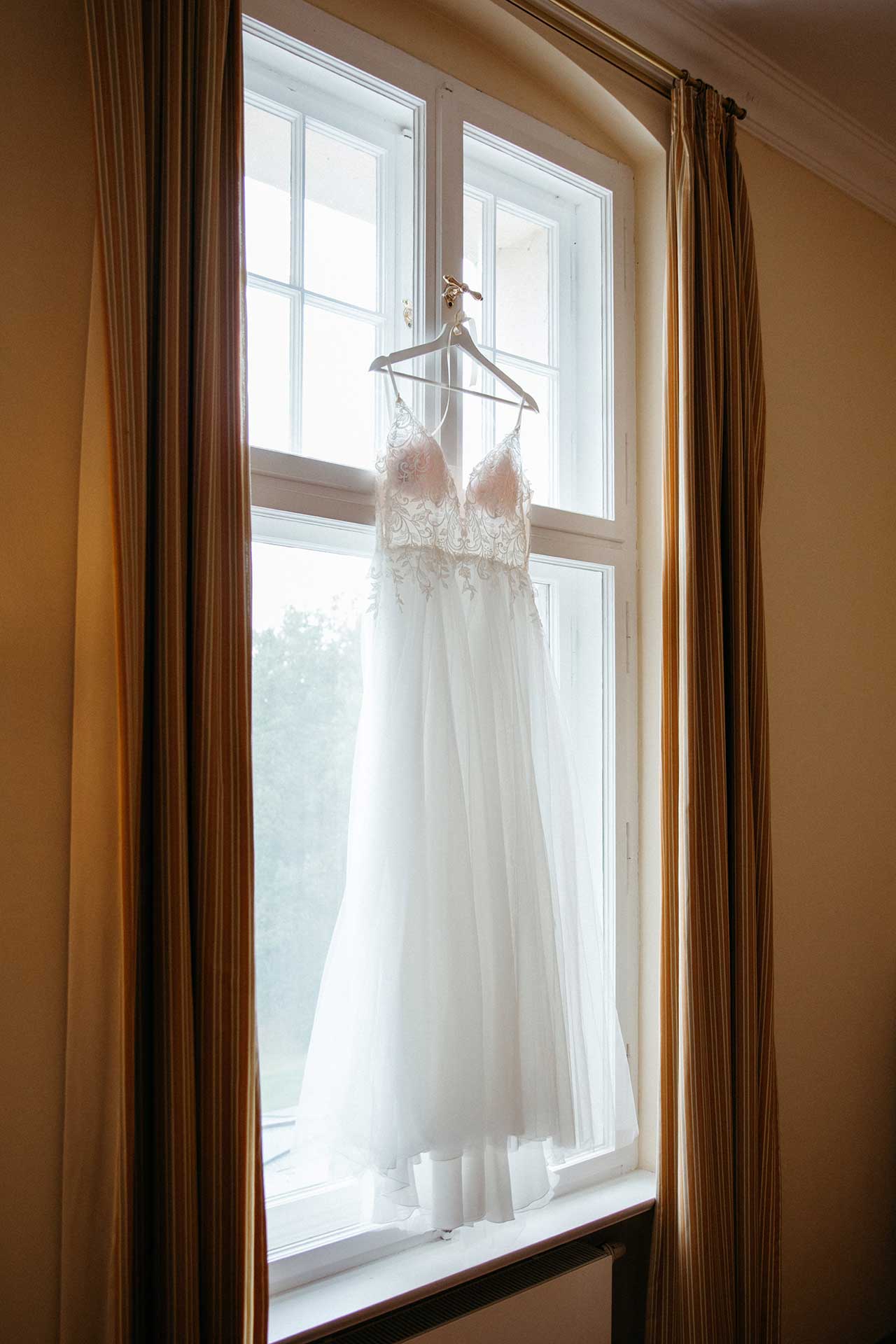Detailaufnahme des Hochzeitskleids im Fensterlicht