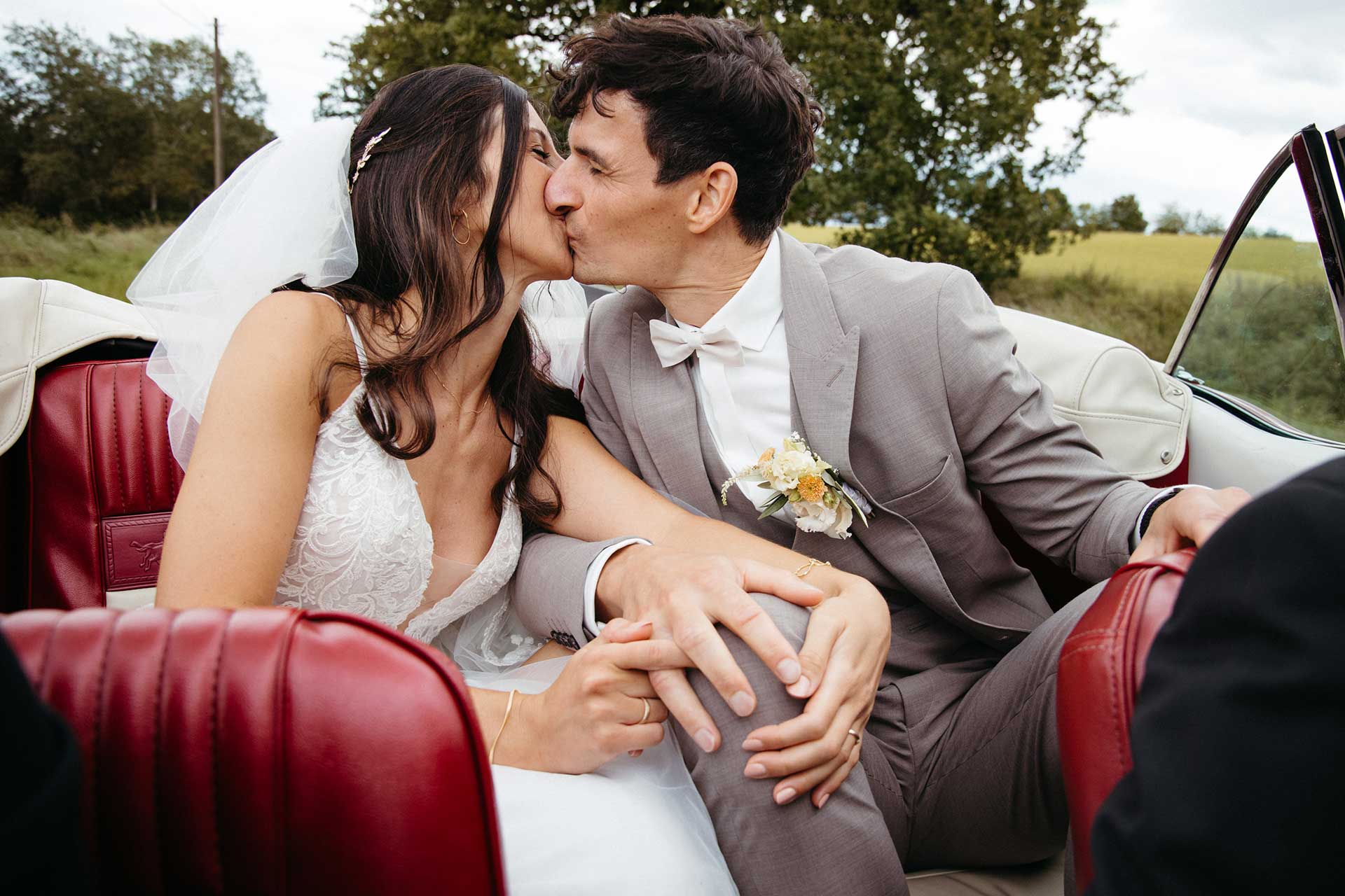 Braut und Bräutigam im Oldtimer – Kuss während der Fahrt